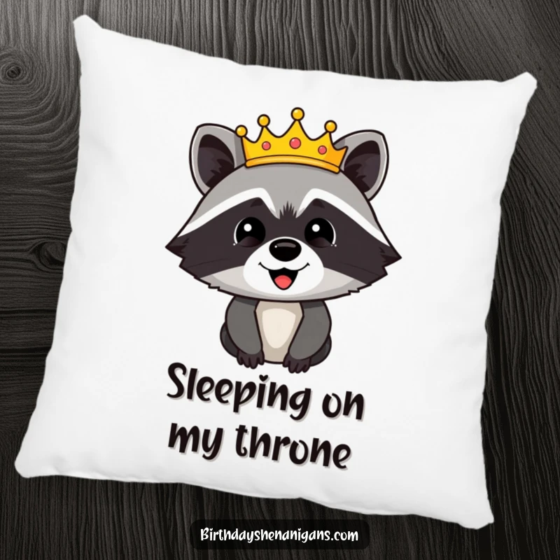Funny pillow featuring a happy raccoon character crowned with a festive, glittering crown, a humorous and cozy addition.