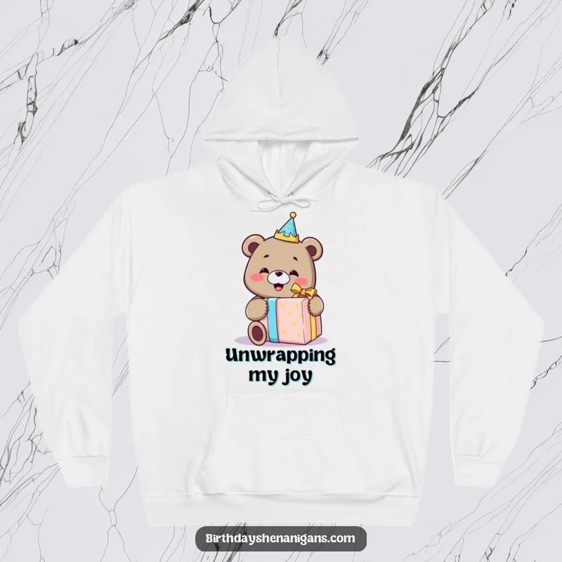 Funny hoodie depicting a smiling bear wearing a birthday crown, gleefully unwrapping a comically huge gift, radiating pure birthday delight.