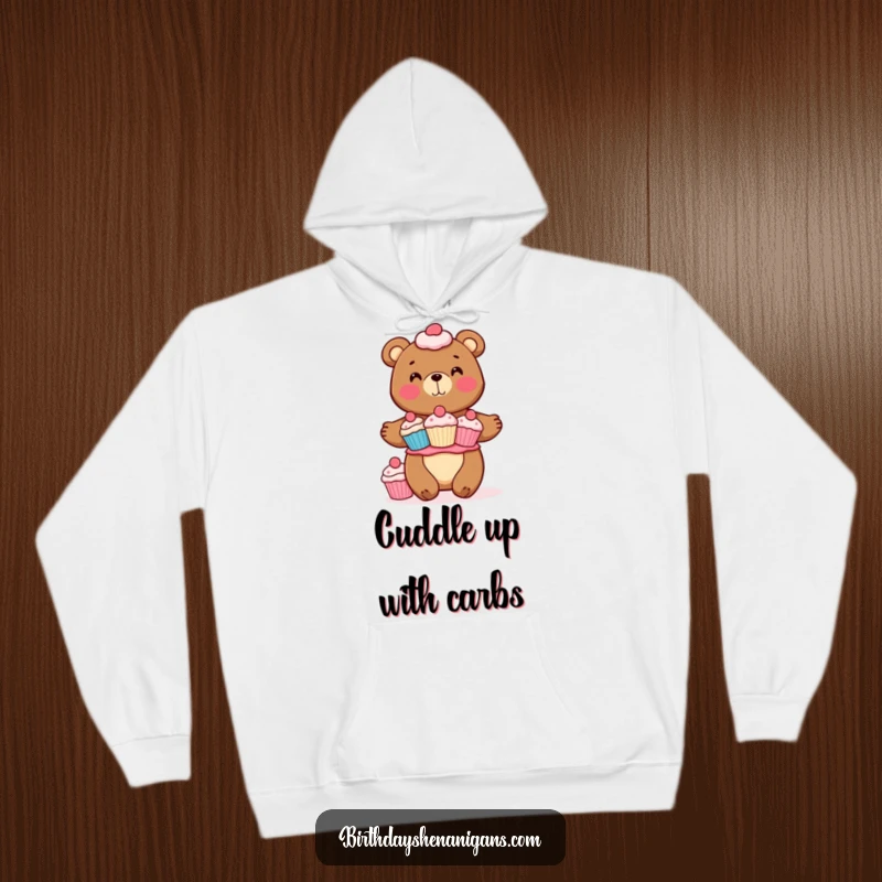 Funny hoodie depicting a happy bear character maintaining perfect balance atop a delectable stack of cupcakes. Warm comfort meets sweet design.