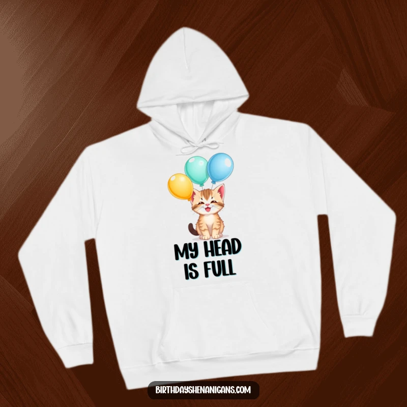 Funny kitten hoodie, cozy, giggling, balancing balloons, playful cat, warm whimsical design, humorous.