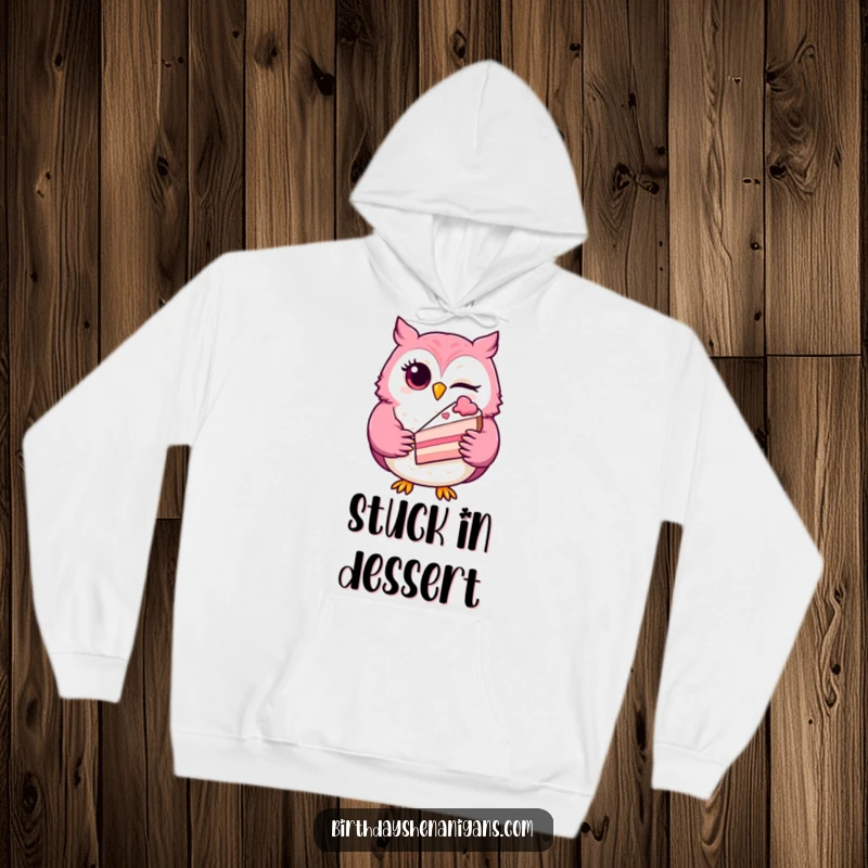 Funny winking owl hoodie, a playful character holding a slice of cake, designed for warmth, comfort, and sweet humor.